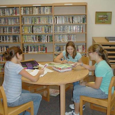 three students working on homework in the library